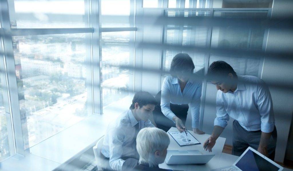 office workers in office obscured by blinds